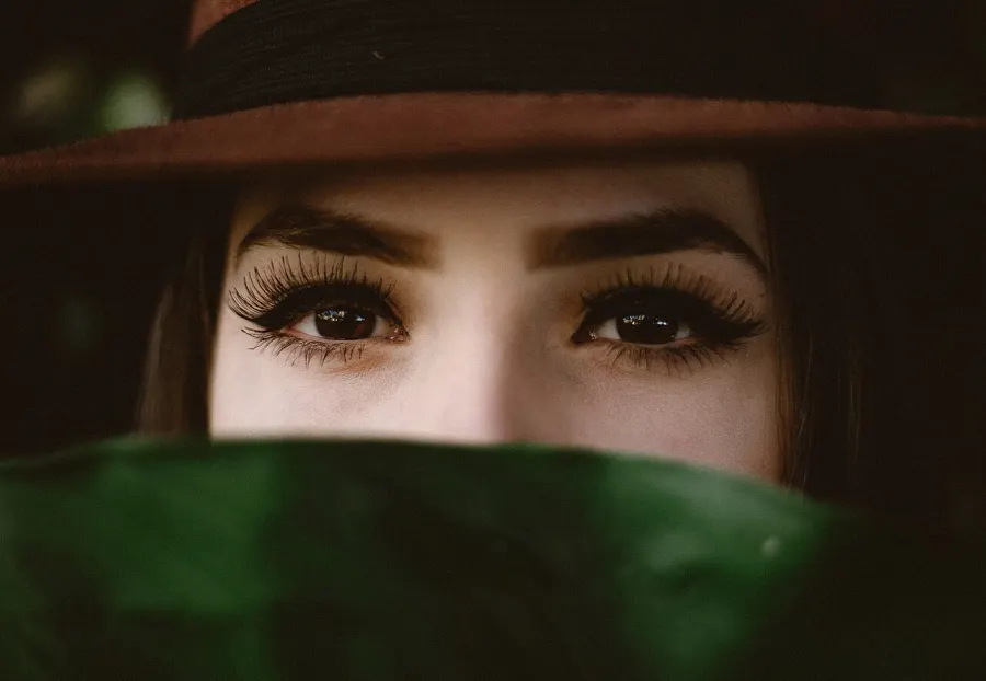 Regard intense aux cils épais, chapeau et foulard vert